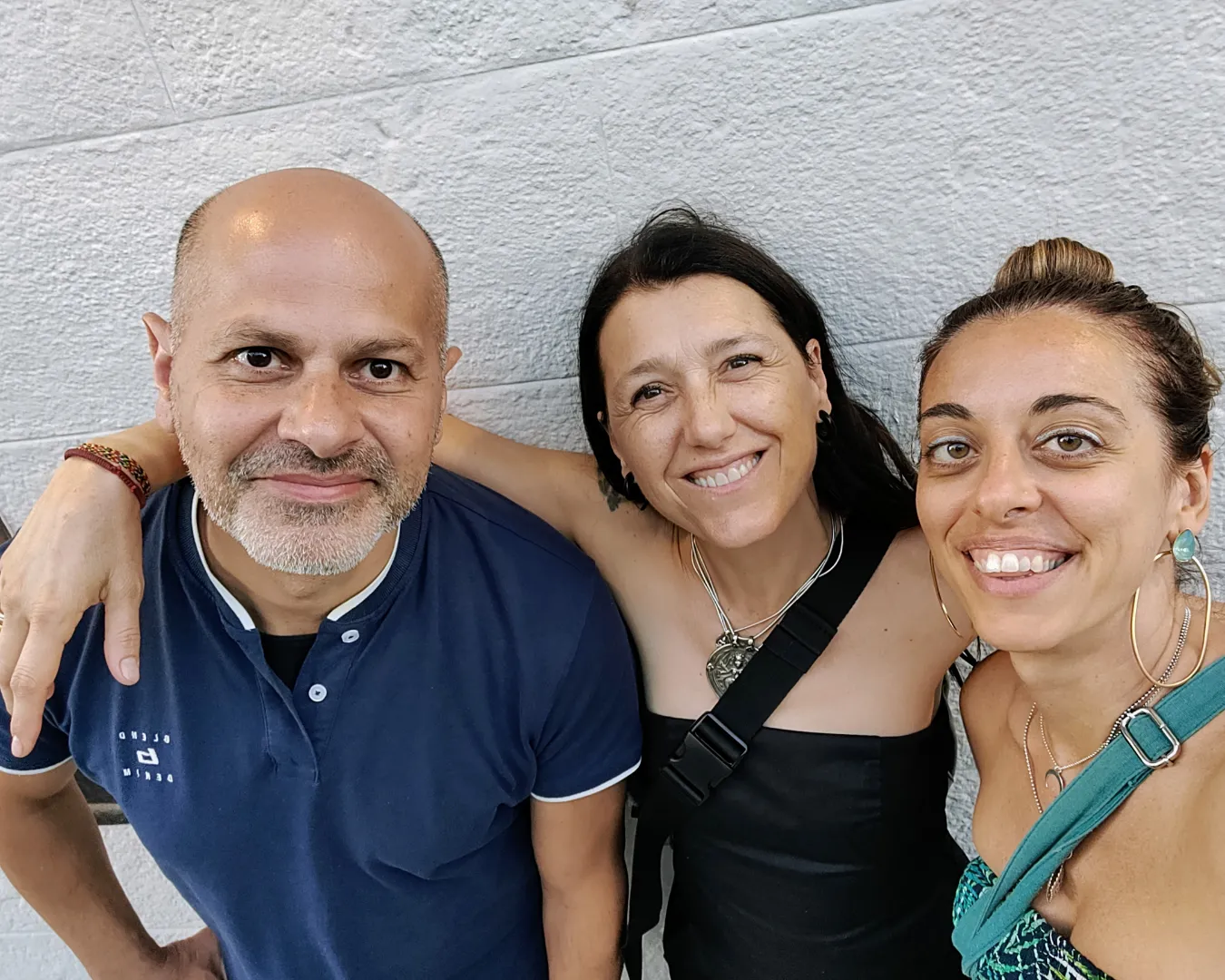 Chiara De Servi sorride insieme a due amici, in uno scatto informale davanti a un muro bianco, simbolo di amicizia e condivisione.