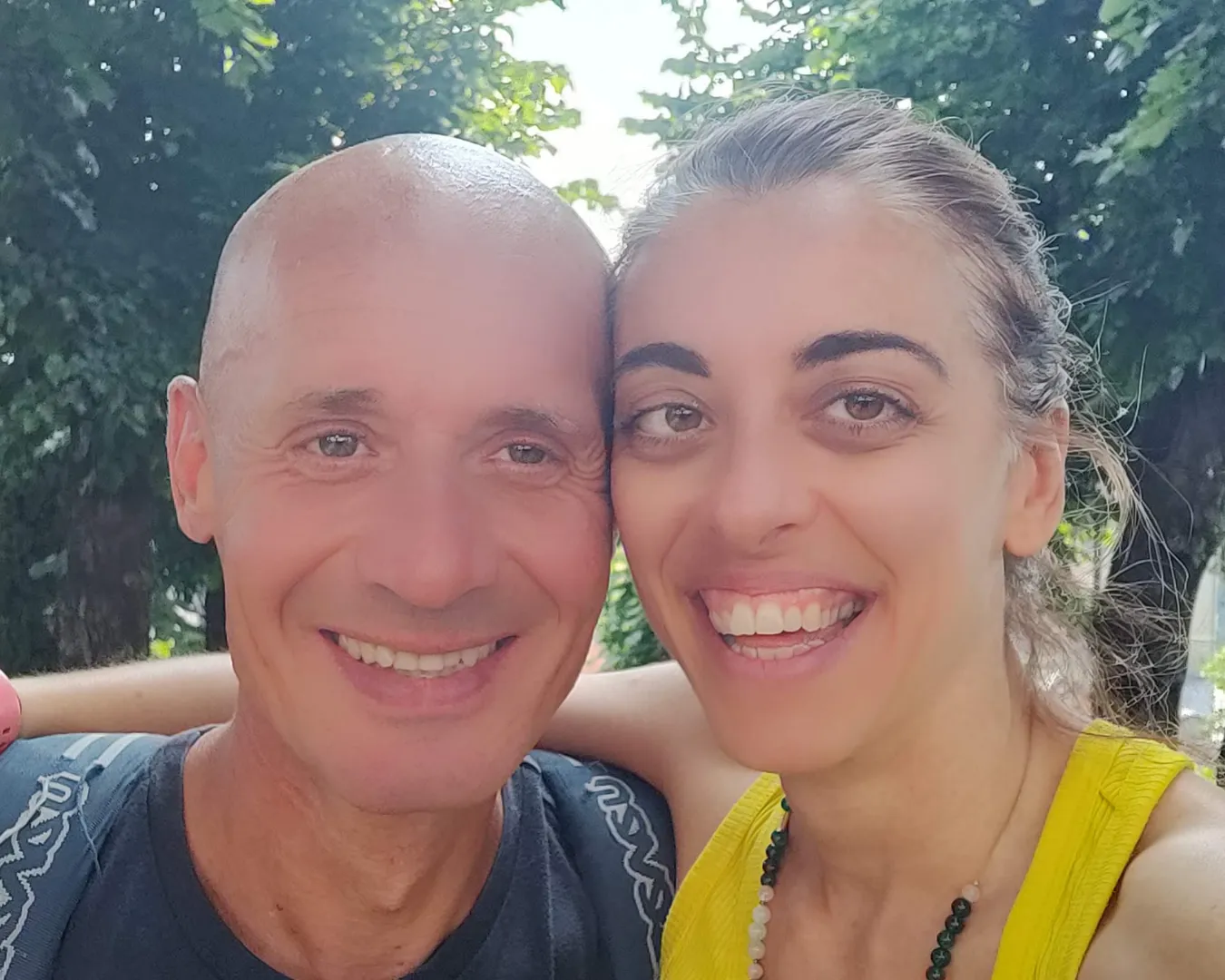 Chiara De Servi abbracciata al suo compagno, entrambi sorridenti durante una giornata estiva all’aperto.