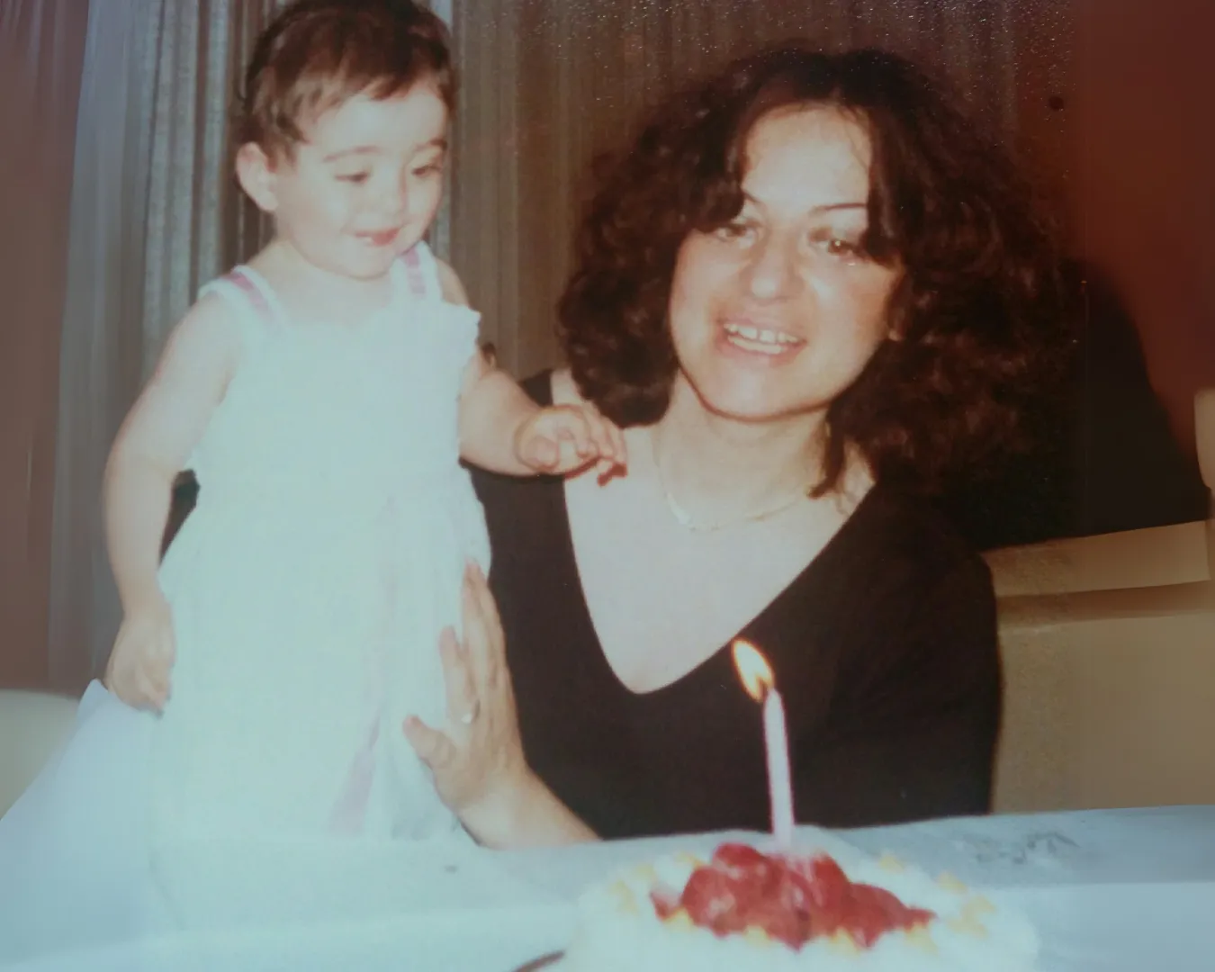 Foto vintage di Chiara De Servi bambina in braccio a sua mamma durante una festa di compleanno con torta e candela accesa