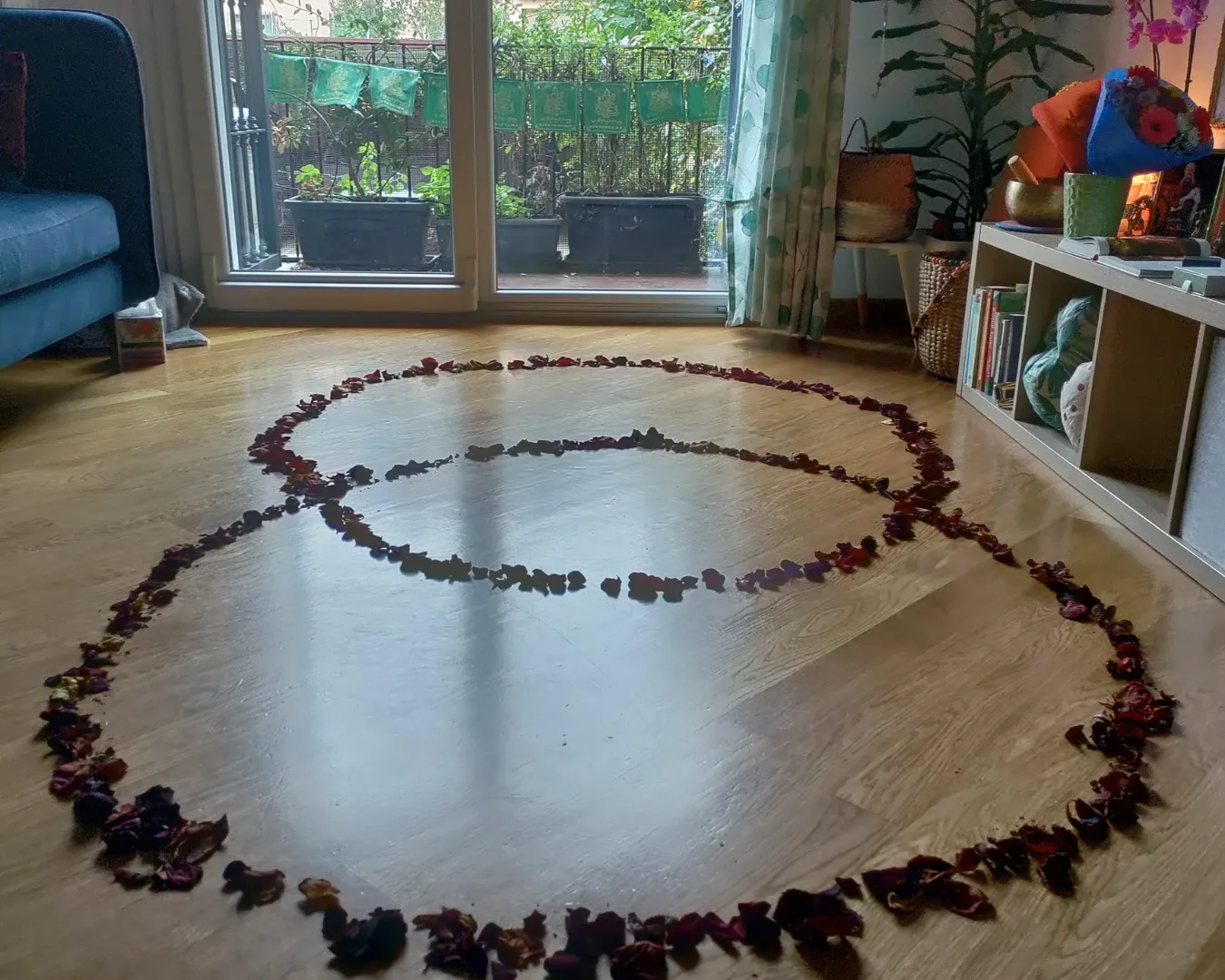 Decorazione simbolica con petali di rosa disposti a cerchio su pavimento di legno in un ambiente domestico accogliente.